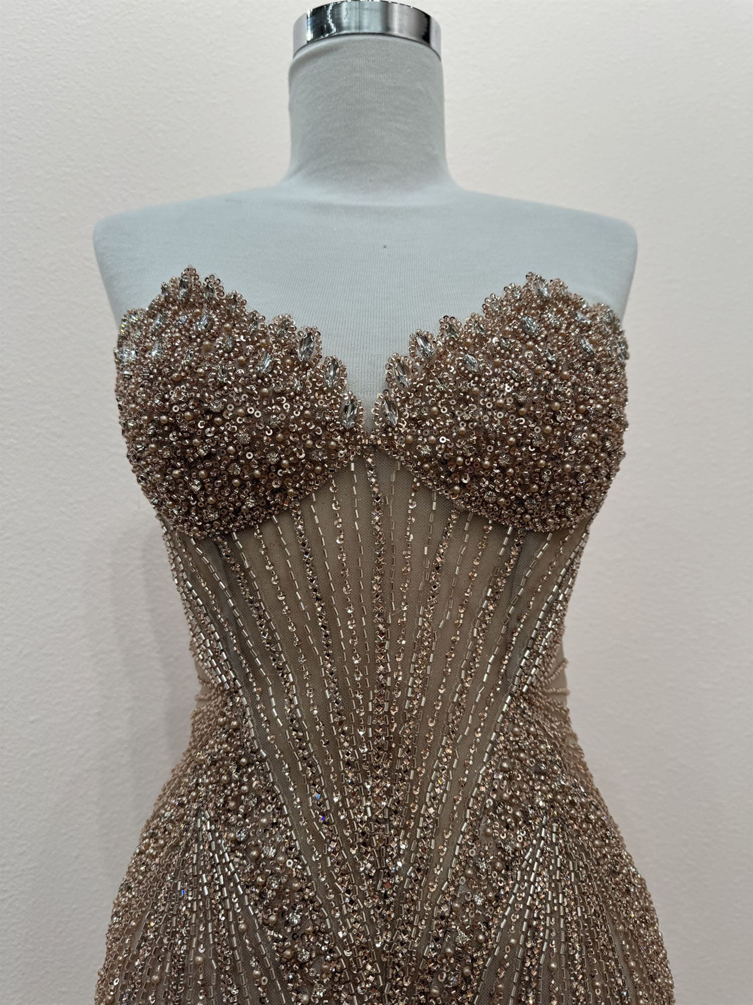 Beaded evening gown on a mannequin against a plain background