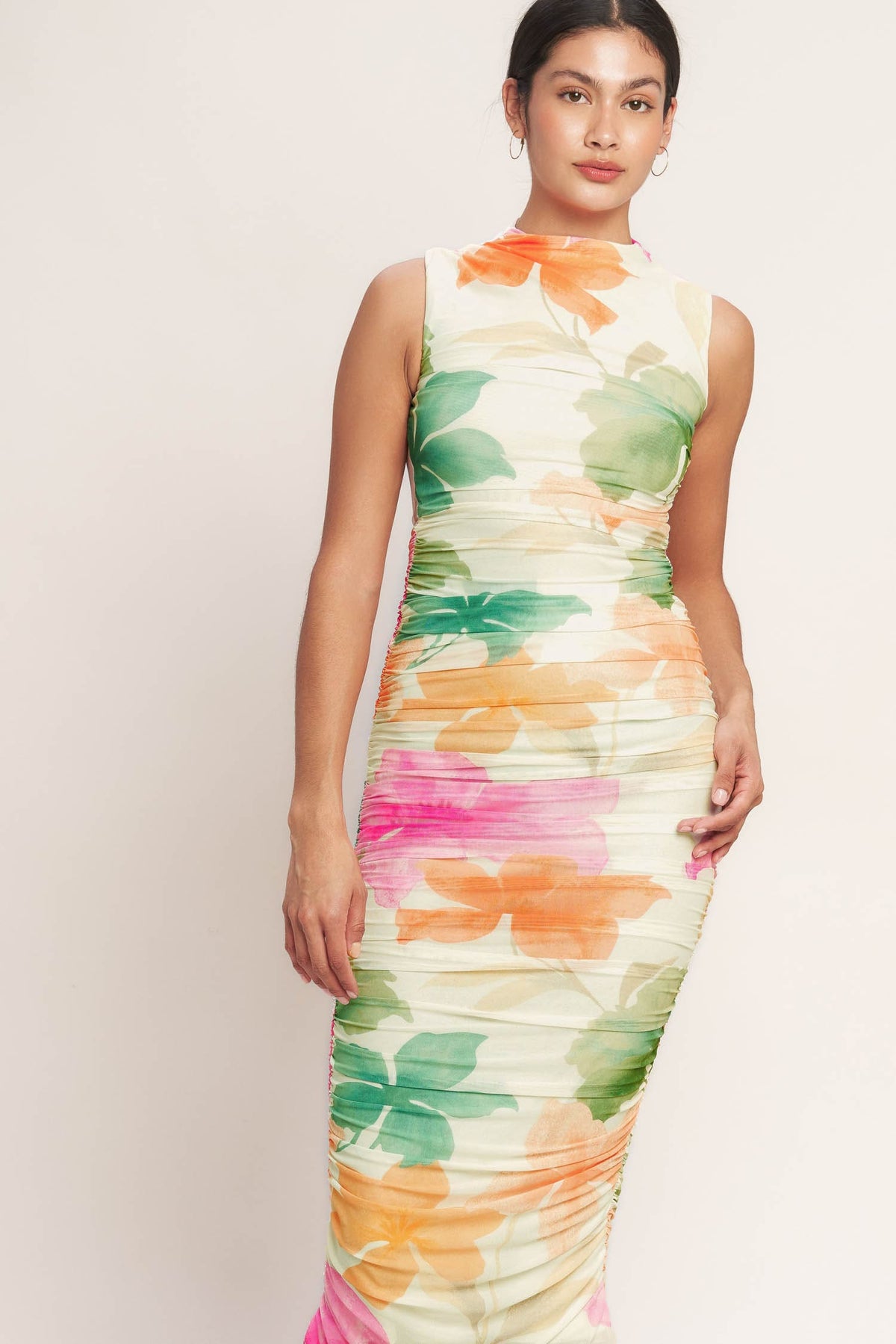 Woman wearing a colorful floral dress against a plain background