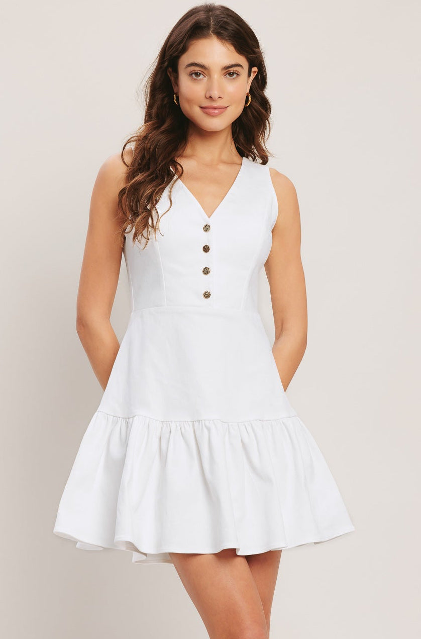 Woman wearing a white dress with buttons on a plain background