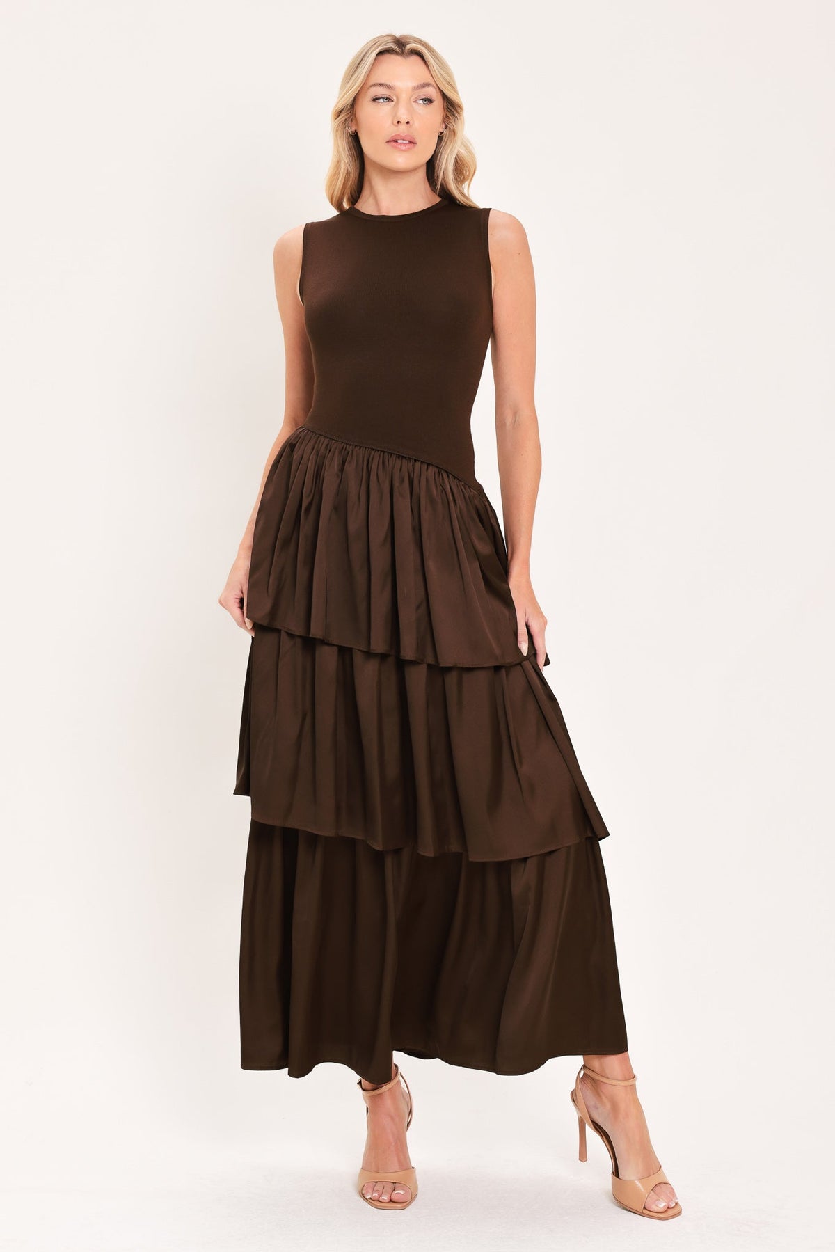 Cocoa Cascade Drop Waist Midi Dress | Lady Black Tie | A woman modeling a sleeveless dark brown dress with a fitted bodice and a tiered maxi skirt