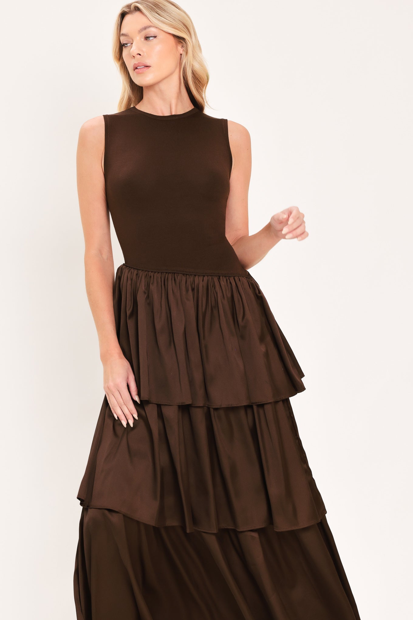 Cocoa Cascade Drop Waist Midi Dress | Lady Black Tie | A woman modeling a sleeveless dark brown dress with a fitted bodice and a tiered maxi skirt