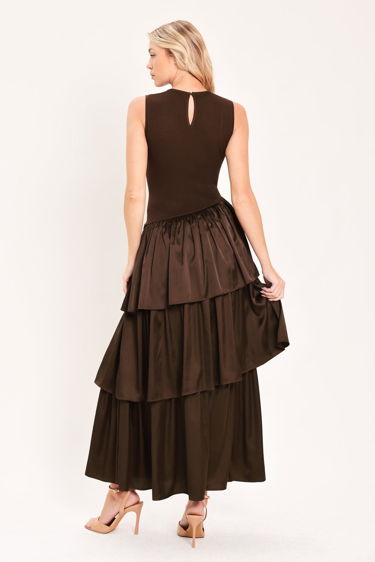 Cocoa Cascade Drop Waist Midi Dress | Lady Black Tie | A woman modeling a sleeveless dark brown dress with a fitted bodice and a tiered maxi skirt