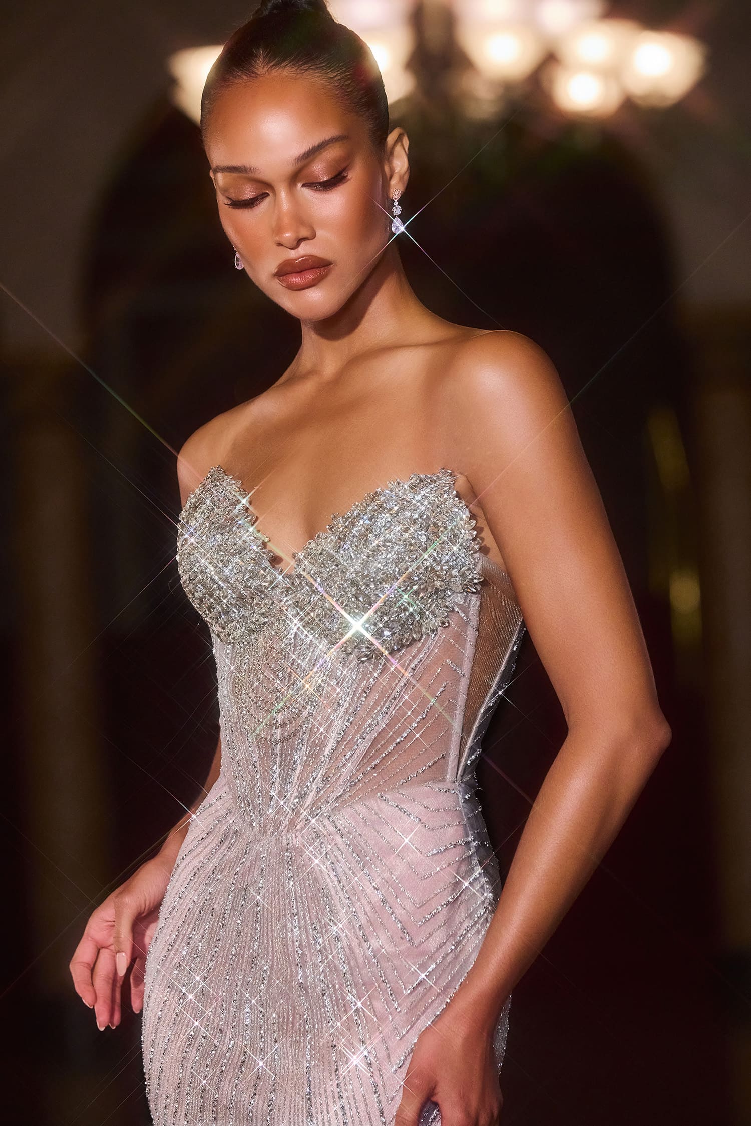 Woman wearing a sparkling silver evening gown against a blurred background