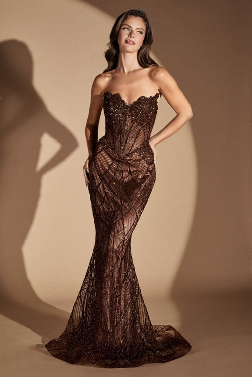 A woman models a strapless, sweetheart-neckline mermaid gown covered in dark brown sequins and beadwork, set against a warm beige studio backdrop with a soft shadow cast to the left.