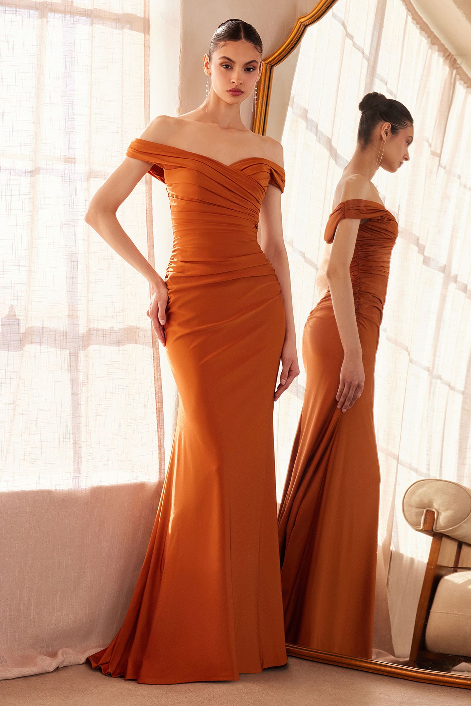 Woman in an orange off-shoulder gown standing in front of a mirror.