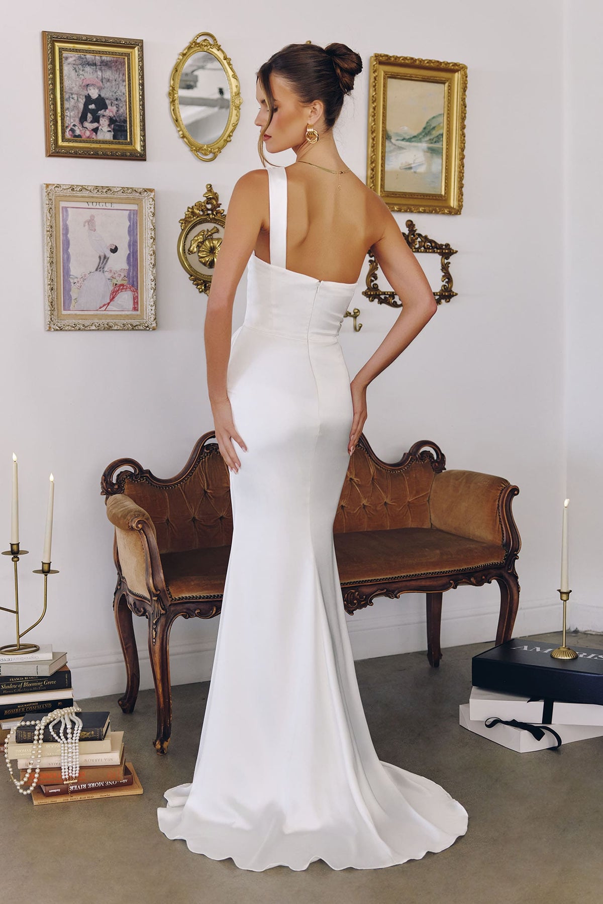 Woman in a white dress standing in a room with decorative elements.