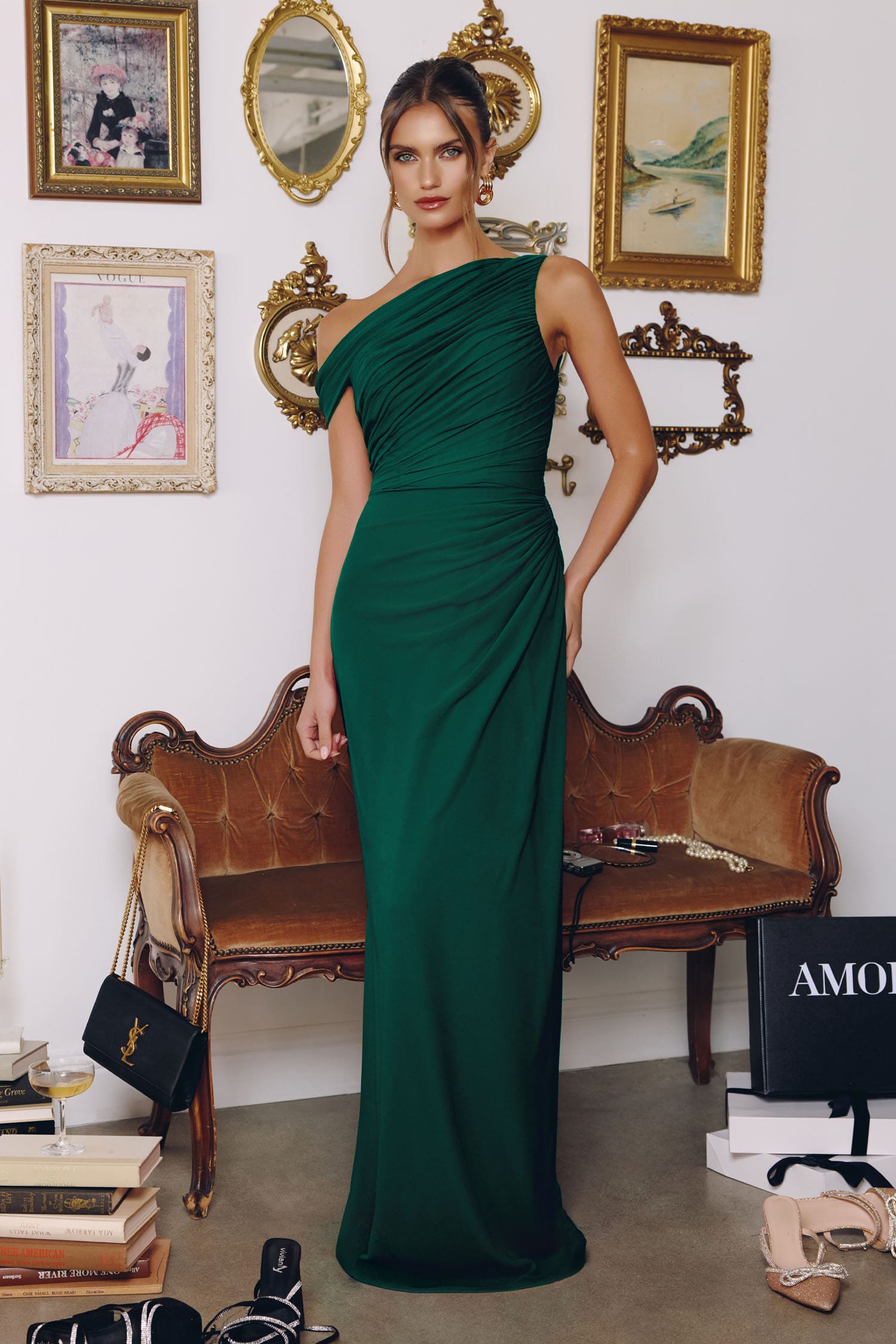 Woman in a green one-shoulder dress standing in a room with vintage decor.