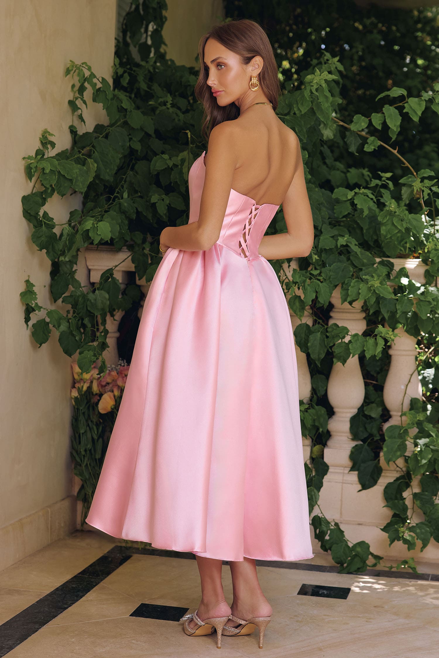Woman in a pink dress standing in front of greenery