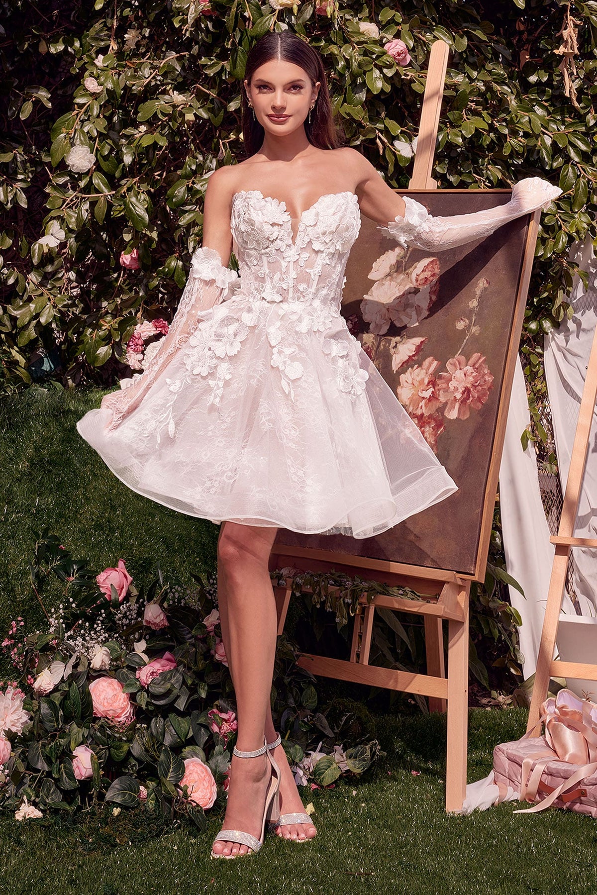 Woman in a white lace dress standing in front of floral decorations