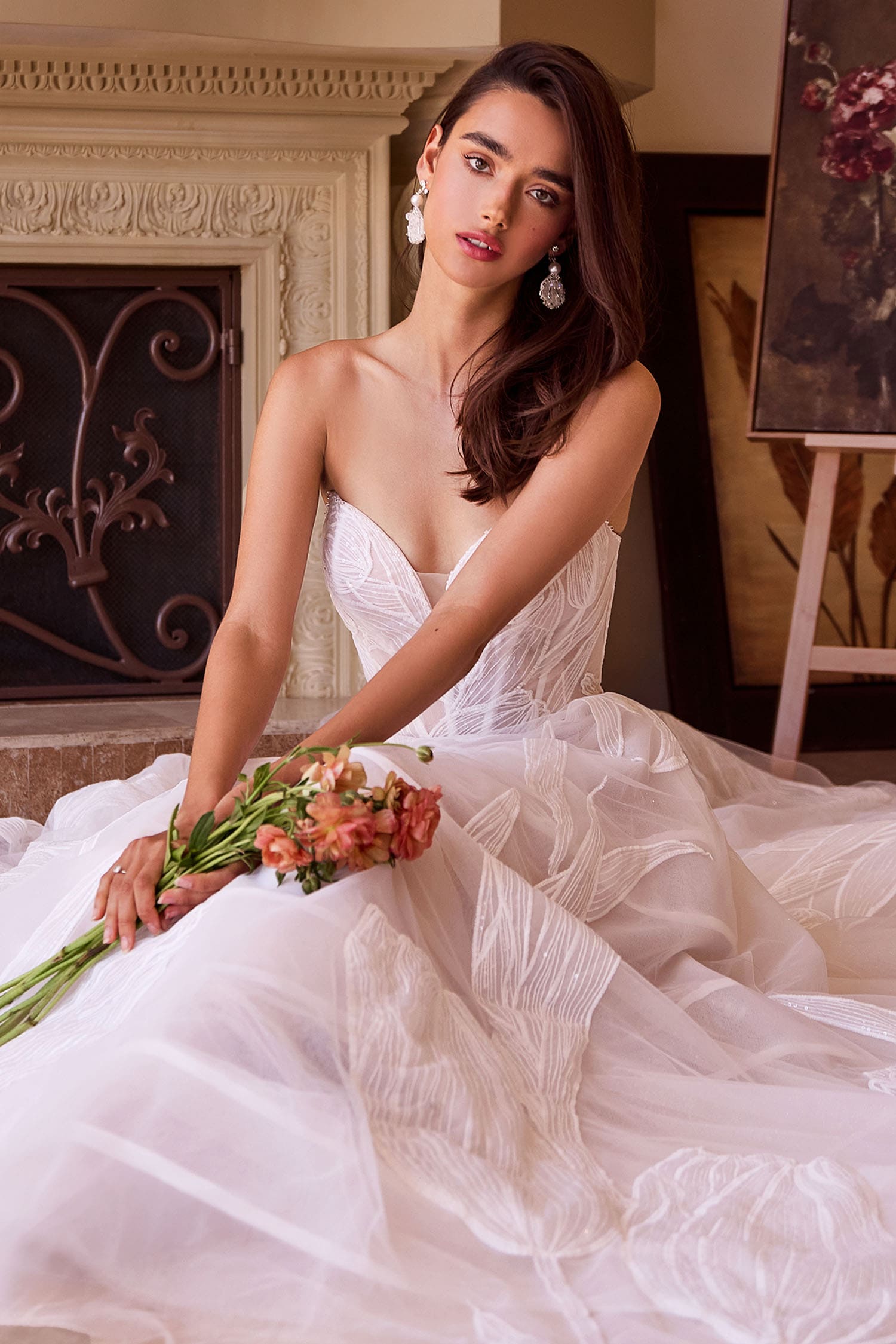 Woman in a white wedding dress holding flowers in an elegant indoor setting.