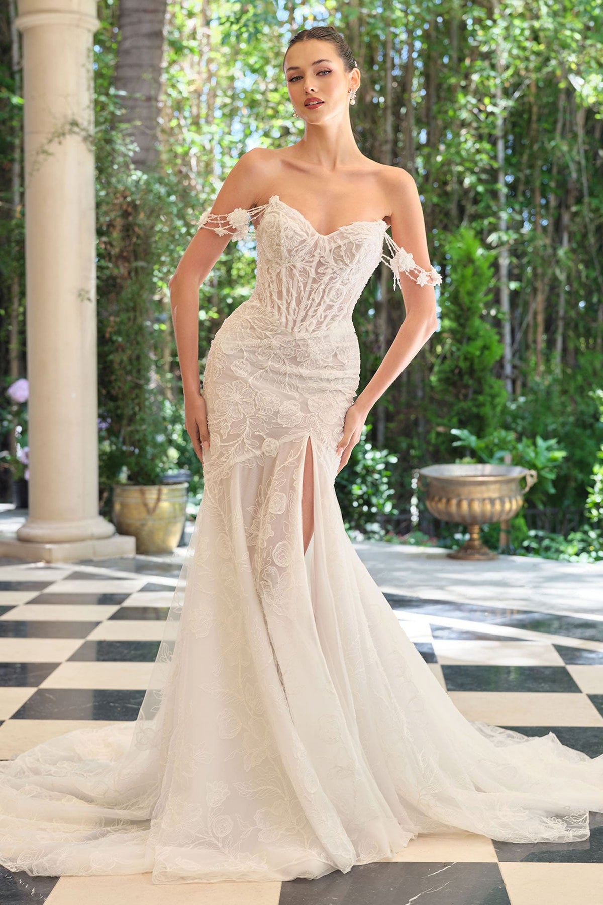 Woman in a white wedding dress standing in an outdoor setting with columns and greenery.