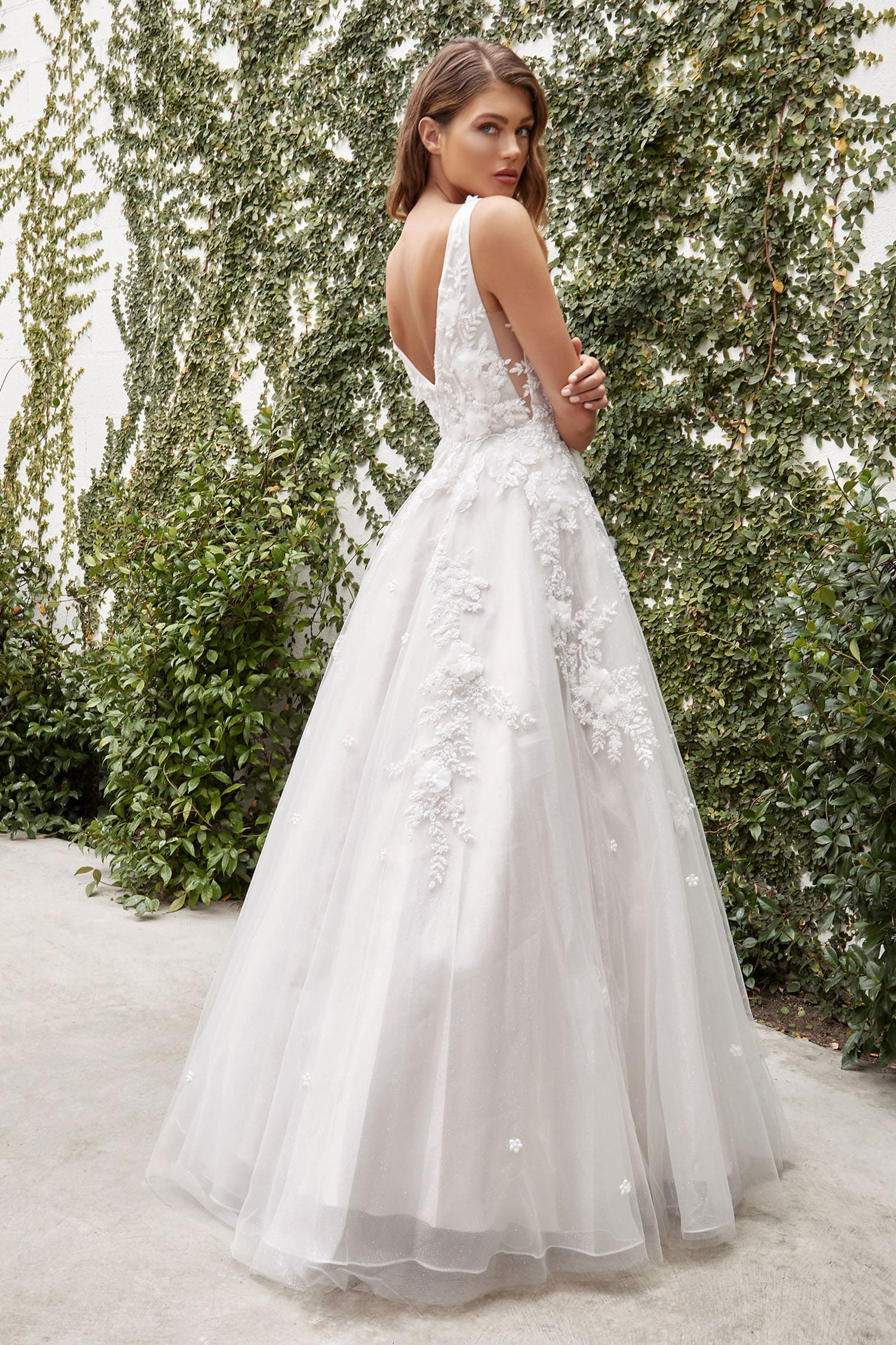 Woman in a white wedding dress standing in front of greenery