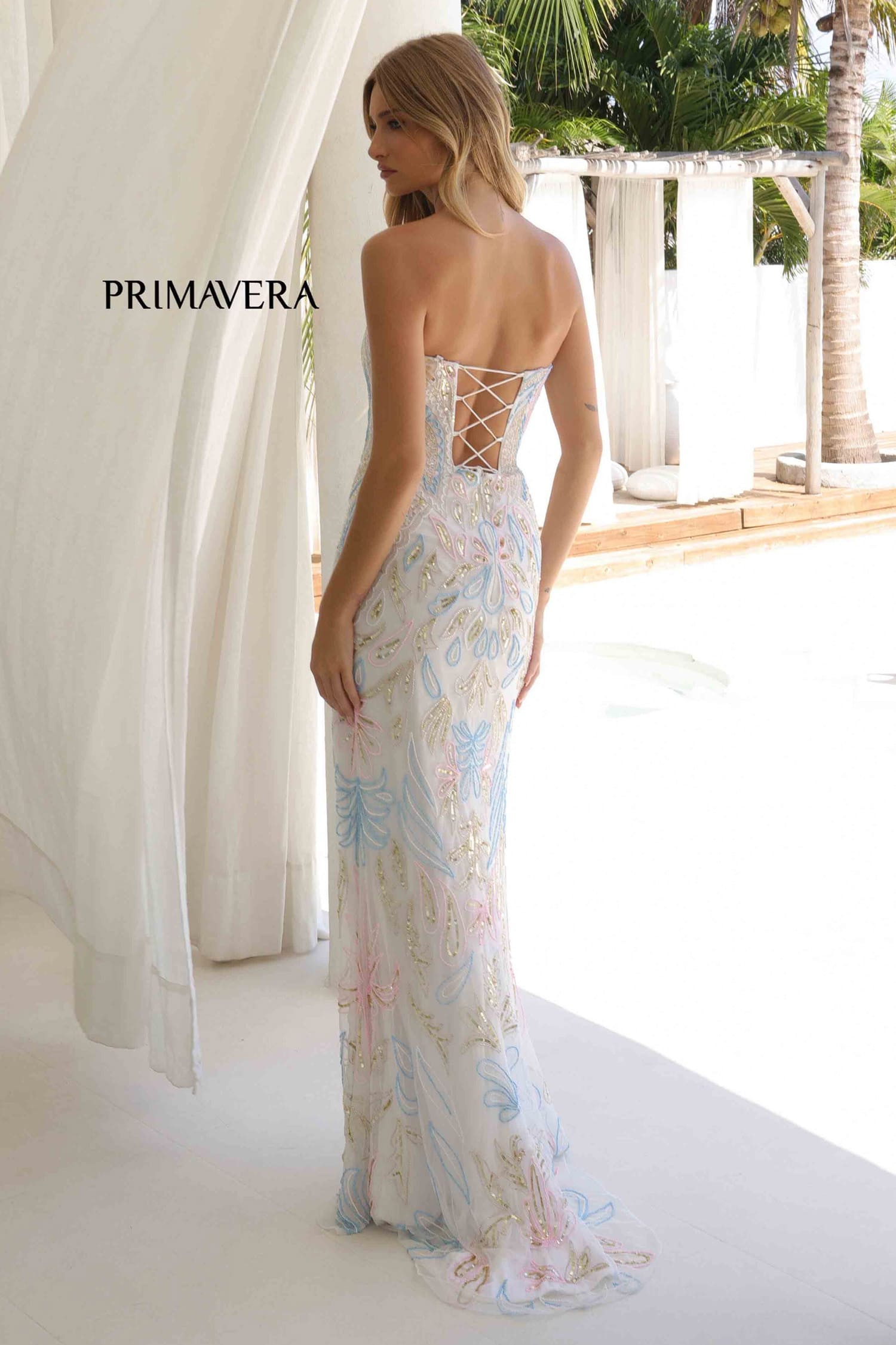 Woman wearing a floral dress with 'PRIMAVERA' branding in an outdoor setting.