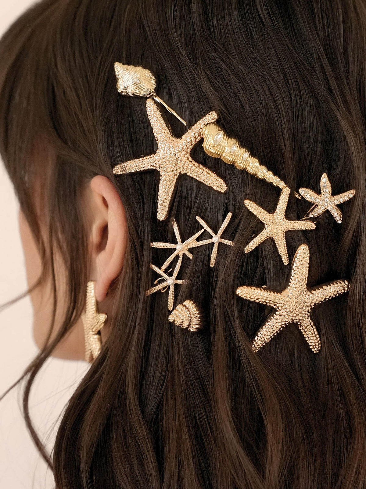 Gold starfish hair accessories on a person's hair against a neutral background