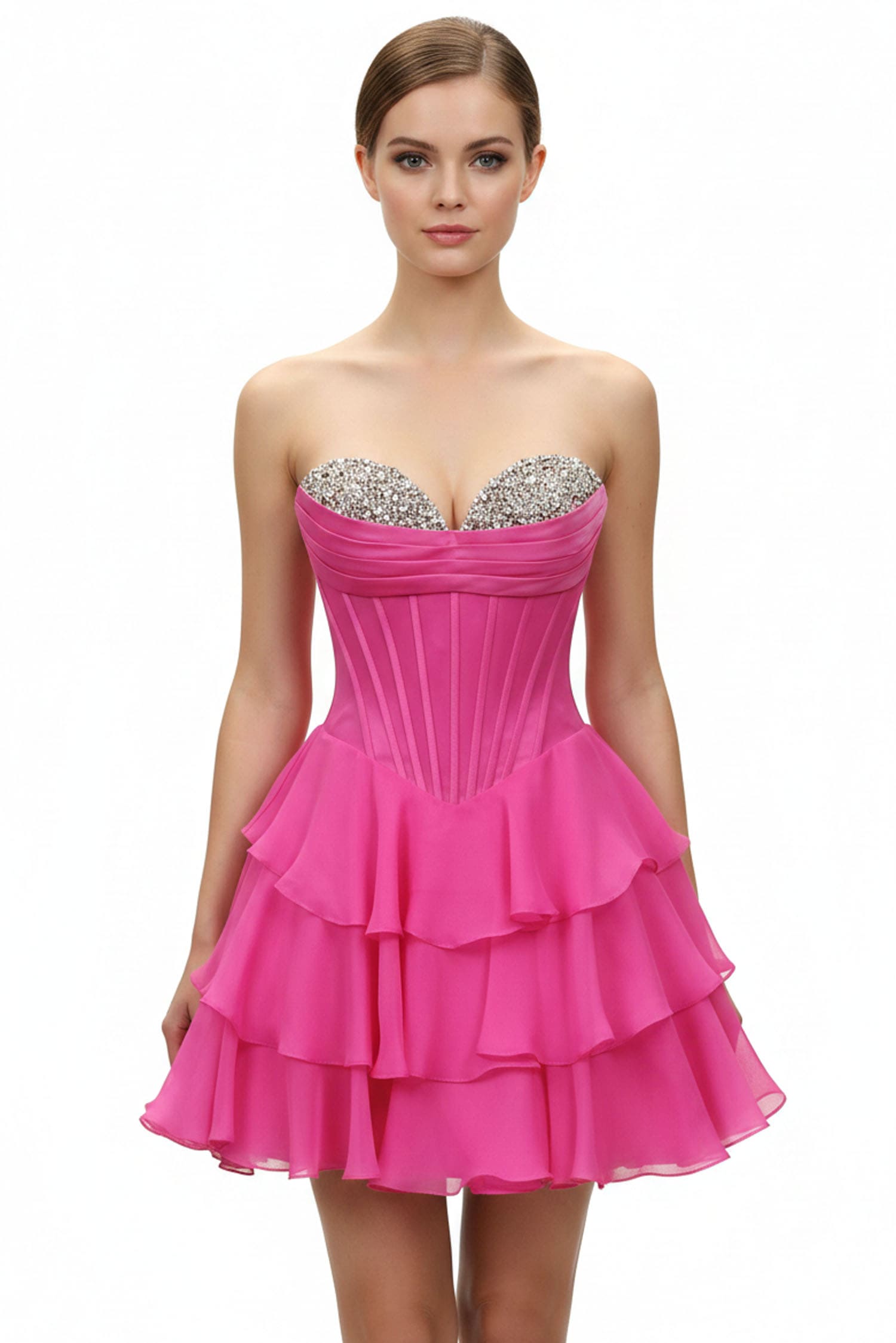 A woman modeling a bright pink strapless mini dress with a corset-style bodice, silver rhinestone embellishments across the sweetheart neckline, and a tiered ruffled skirt, set against a plain white background.