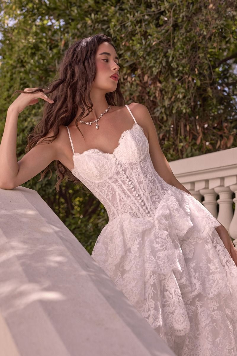 WL076 - LAYERED SCALLOP LACE A-LINE GOWN - Andrea & Leo | Lady Black Tie | A woman wearing a white lace corset dress with thin straps and a ruffled skirt.